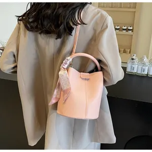 Détail du sac seau en cuir rose texturé orné d'un élégant foulard en soie imprimé