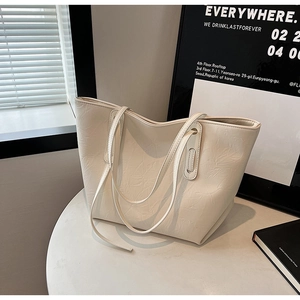 Close-up of the floral embossed texture on a cream white leather tote shoulder bag