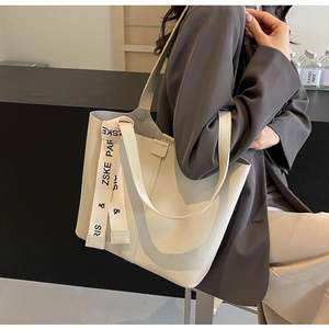 Close-up of beige lychee grain leather tote bag featuring a branded woven strap detail