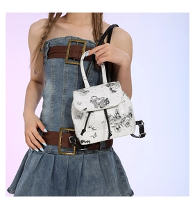 Detailed view of white mini backpack with black butterfly prints worn on a casual outfit