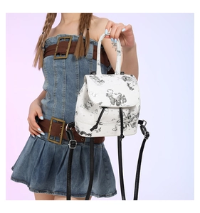 Detail of a white mini backpack with butterfly print held by a model in denim