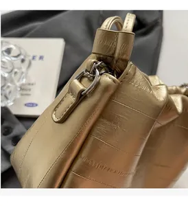 Detail of metallic gold quilted handbag showing silver D-ring hardware and textured finish