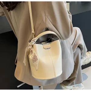 Détail du sac seau en cuir blanc crème avec texture lychee et décoration en foulard