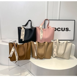 Five assorted tote bags with litchi texture and silk scarves on minimalist display