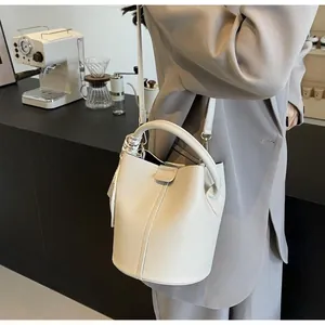 Détail d'un sac seau en cuir grainé beige avec foulard en soie sur la poignée