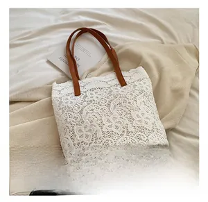 Close-up of white floral lace tote bag with brown leather handles and inner lining