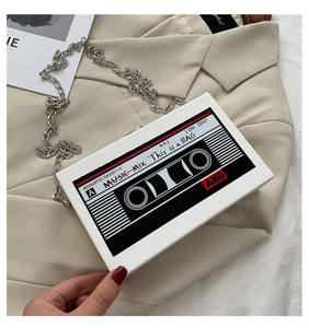 Macro shot of retro cassette shaped clutch bag with silver chain on beige blazer