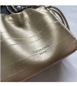 Macro view of gold pleated chain bucket bag showing soft metallic texture and brand logo