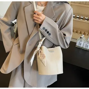Détail du sac seau blanc crème avec texture en cuir grainé et foulard en soie sur l'anse