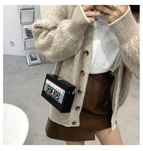 Detail view of retro cassette tape shaped crossbody bag with silver chain and music print