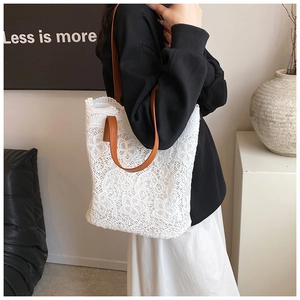 Close-up of white lace pattern texture and brown leather handle on a women's tote bag