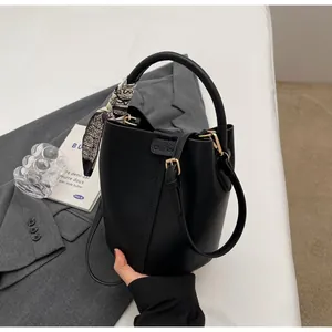 Détail du sac seau noir grainé avec poignée en foulard et ferrures dorées