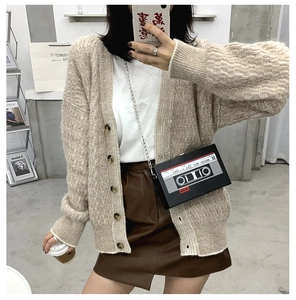 Black cassette shaped crossbody bag styled with a white knit cardigan and brown leather skirt