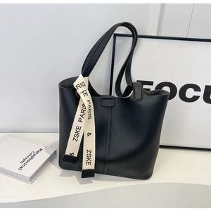 Close-up of black lychee leather tote bag with stylish printed cream woven ribbon detail