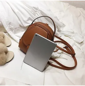 Mini brown leather backpack shown next to a tablet to demonstrate compact storage size