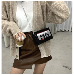 Close-up of retro cassette tape shaped shoulder bag with chain strap worn by a model