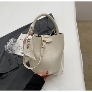 Détail du sac seau en cuir blanc cassé avec foulard en soie et bandoulière réglable