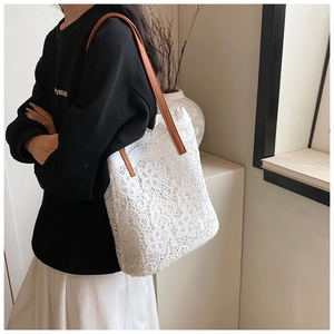 Detailed close-up of white floral lace tote bag with brown leather handles and hollow pattern