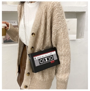 Close-up of retro cassette tape shaped crossbody bag with silver chain strap worn by model