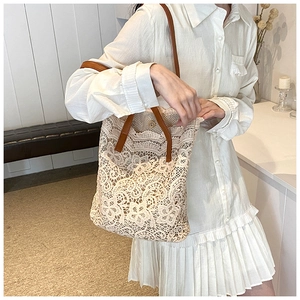 Detail of floral lace tote bag featuring brown leather handles and metal magnetic closure