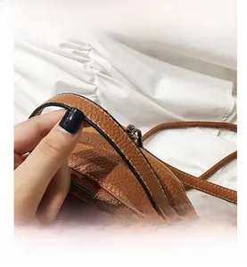 Close-up of brown litchi pattern leather mini backpack handle with golden zipper details