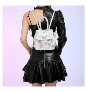 White mini backpack with silver butterfly prints and rhinestone buckle worn by model