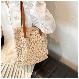 Detailed close-up of beige floral lace tote bag with brown leather handles in a chic setting