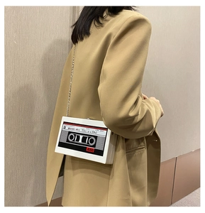Detail view of radio-style white crossbody bag with chain strap on a model's shoulder