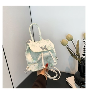 Detail of white PU leather backpack with green butterfly pattern and silver buckle
