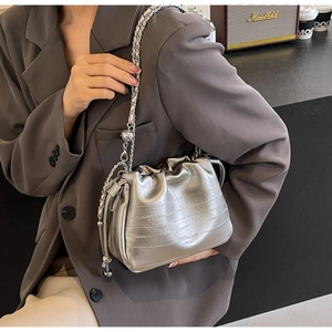 Detail shot of silver bucket bag with crocodile texture and metal chain strap