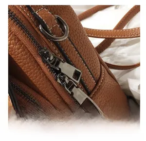 Detail of brown litchi pattern leather backpack with premium silver dual zippers