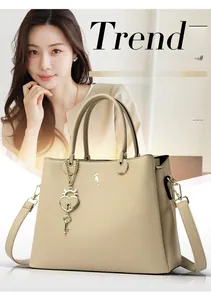 Detail of off-white lychee leather tote bag featuring heart pendant and shoulder strap
