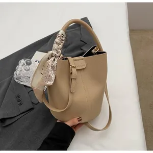 Vue détaillée du sac seau en cuir beige avec un foulard décoratif en soie sur l'anse