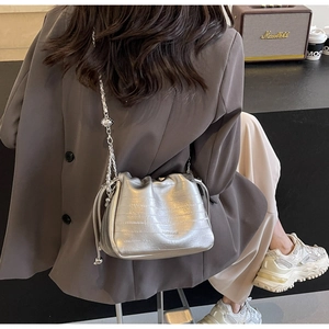 Detail of silver croc-embossed chain shoulder bag with drawstring side and metallic finish