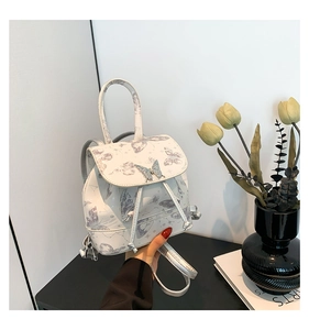 Detail of white backpack featuring lavender butterfly prints and silver metal buckle