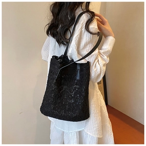 Detail of black lace tote bag featuring intricate floral crochet patterns and slim straps