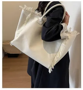 Close-up of oversized cream canvas tote bag with fringe edge detail and wide handle