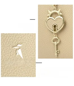 Detail of beige lychee leather bag with gold heart lock and key pendant detail
