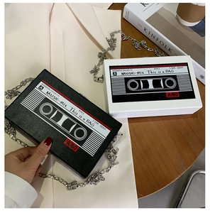Detail of retro cassette tape shaped box bags with silver chains on wooden table