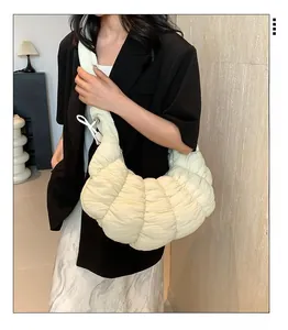 Vue latérale d'un sac demi-lune plissé beige porté à l'épaule dans un style chic