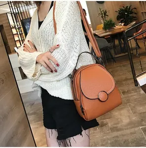 Detail view of orange-brown pebble leather mini backpack with metal ring buckle and dual zippers
