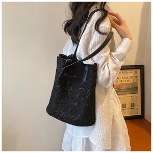 Close-up of black floral lace tote bag with synthetic leather straps on woman's shoulder