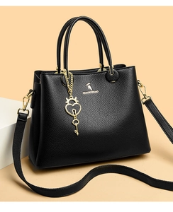 Detailed view of black litchi pattern leather tote bag with heart pendant and long strap