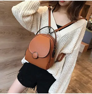 Detail view of brown lychee-grain leather mini backpack with adjustable straps and round buckle