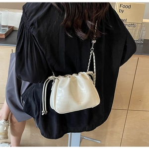 Close-up of cream-white crocodile embossed bucket bag with chain strap and drawstring