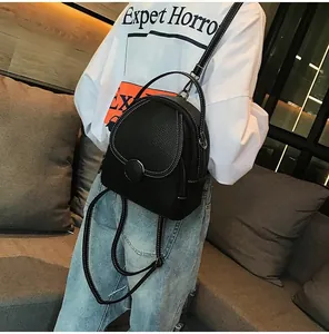 Detail of black pebbled PU leather mini backpack with contrast white stitching and round buckle
