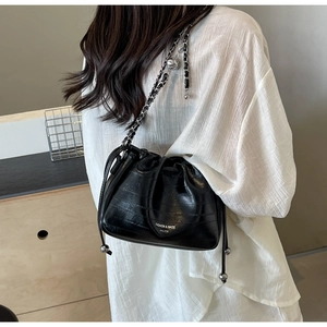 Detail of black drawstring bucket bag with silver chain strap and logo lettering