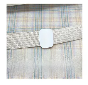 Detail of adjustable cream woven shoulder strap with white buckle on plaid fabric