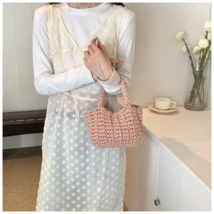Dettaglio della borsa intrecciata rosa con trama in maglia spessa e manici alla moda