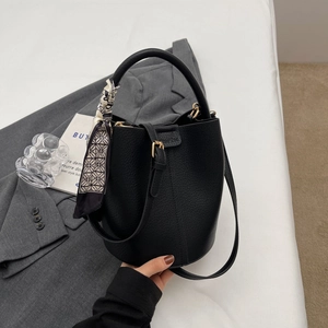 Sac seau minimaliste en cuir noir avec foulard géométrique sur la poignée et détails dorés